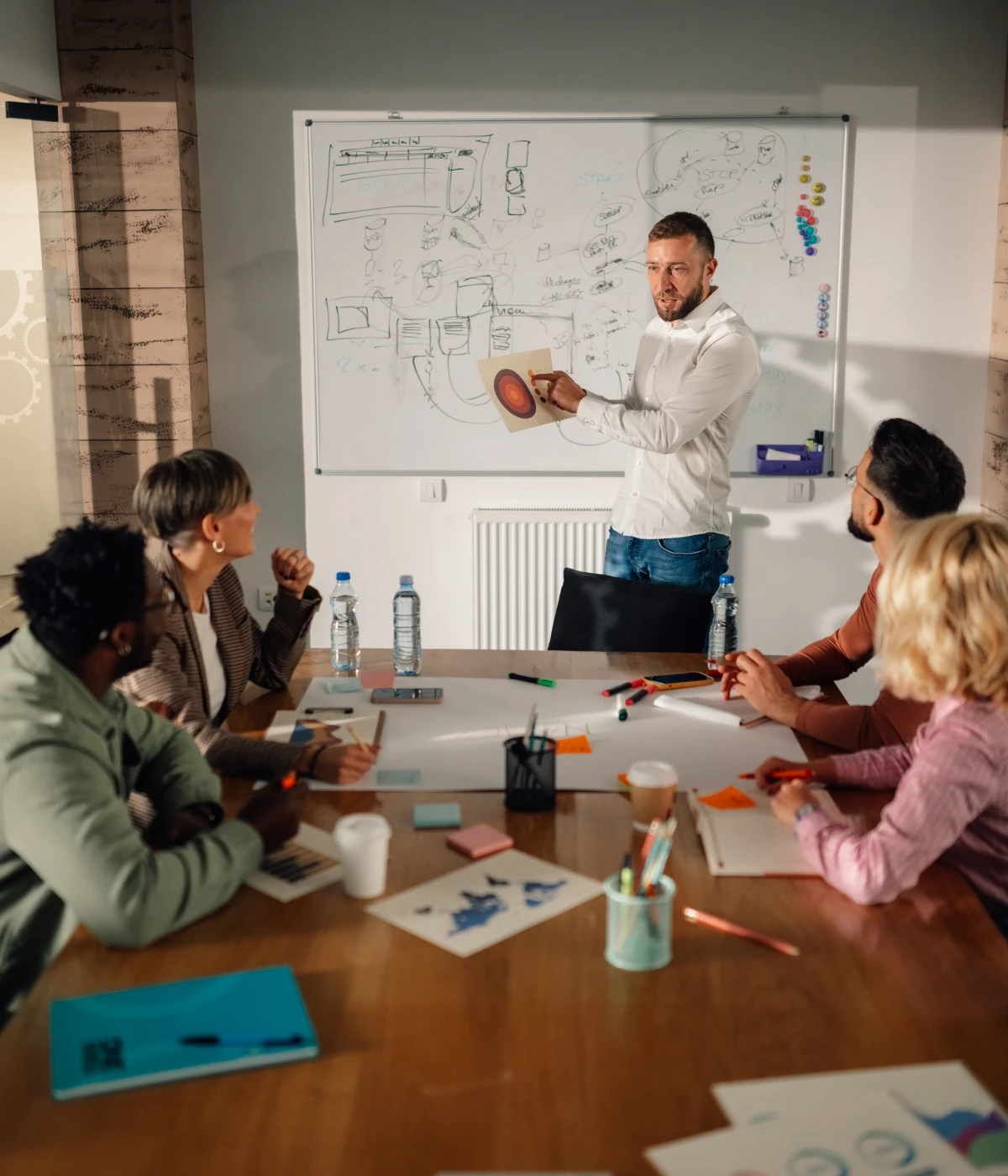 Man presenting on whiteboard to colleagues